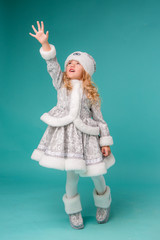 little blonde girl smiling in snow maiden costume isolate on blue background, baby catches snowflakes