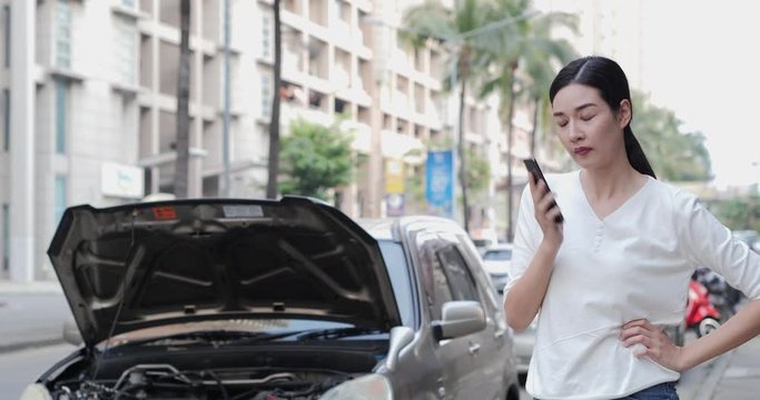 Asian woman using phone to talk with insurance with serious emotion. Her having problem at the road.