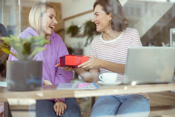 Positive delighted birthday girl looking at gift box