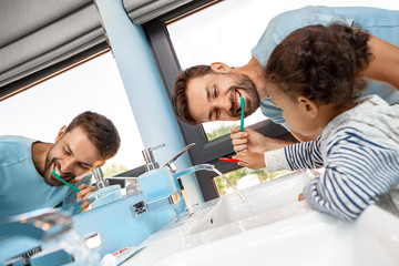 Father brushing teeth in bathroom with daughter