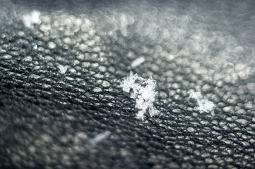 small snowflakes on a black leather glove, close-up, macro photo