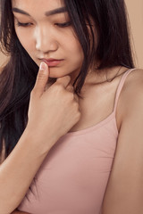 Freestyle. Asian girl in top standing isolated on grey touching lip tender looking down pensive close-up