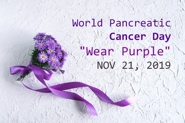 World Pancreatic Cancer Day "Wear Purple" November 21, 2019 text on white textured background with purple flowers and purple ribbon. Flat lay, top view.                                       