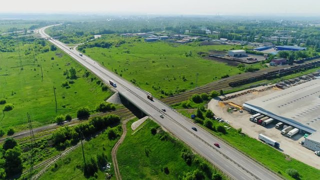 highway near large warehouse and green field aerial view