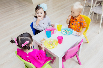 Little children eating breakfast in the kindergarten