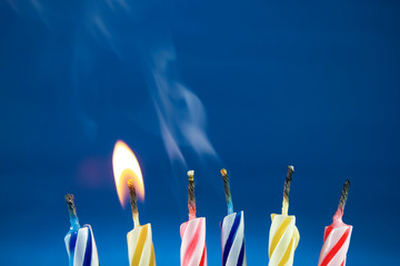Colorful and fun birthday candles are being blown at a party. One candle is still lit and the other...