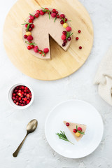 Slice of raw cheesecake with cocoa, banana and berries on a white plate.