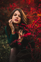 Beautiful woman posing on red tree leaf background.