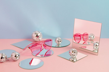 Festive party background with disco balls, mirrors and sunglasses over pink and blue backdrop
