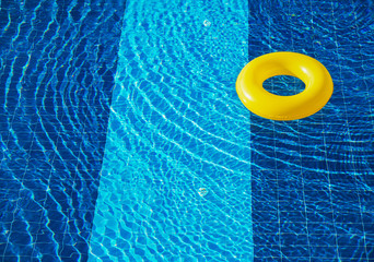 Yellow pool float, ring floating in a refreshing blue swimming pool