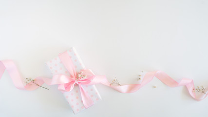 gift box for woman - polka dot paper, pink bow, little flowers. Flat lay or top view.