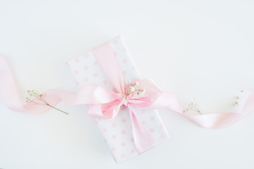 gift box for woman - polka dot paper, pink bow, little flowers. Flat lay or top view.