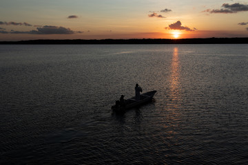 silhouette of boat and men at sunset