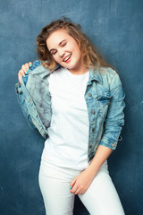 young pretty blond girl posing happy smiling on blue background interior, lifestyle people concept