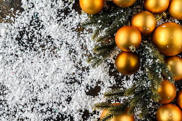 Fototapeta na wymiar Christmas Flat Lay, new year background. Gold baubles on Dark Background, White snowflakes on a spruce branch. Selective focus. Minimalistic design. Space for text