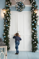 boy enters house with christmas decoration.little boy peeps through a keyhol. House decorated for Christmas. Merry Christmas and Happy New Year.