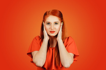 redhead young woman covering ears looking at camera