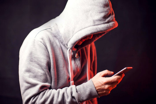 Man Wearing Hoody Sweater With Phone In Hands. Crime And Hacking Concept