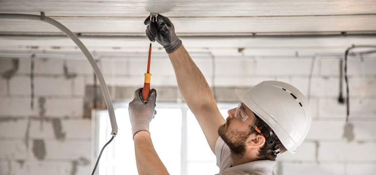 Electrician Installer With A Tool In His Hands, Working With Cable On The Construction Site.