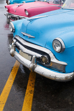 colored almendrones parked on the street in the rain , havana - cuba