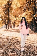 Beautiful woman drink coffee, using phone and walking in the park.