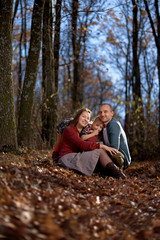 Fototapeta premium Young happy Parents with daughter among autumn leaves. Happy family resting in a beautiful autumn forest
