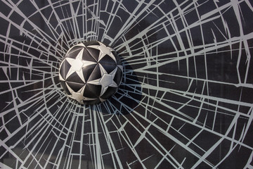 black and white soccer ball with stars in a broken window