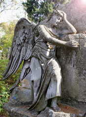 Fototapeta na wymiar A tired angel prays at the cemetery. The concept of death