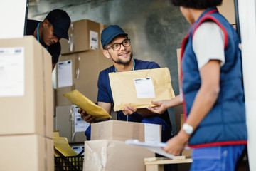 Manual workers cooperating while sorting packages in a delivery van.