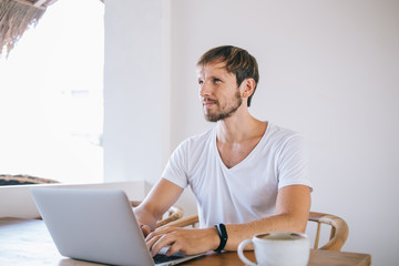 Man typing on laptop and looking up