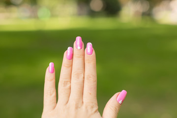 female hand with pink manicure. female hands on the grass.
