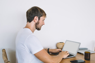 Young freelancer working with laptop at wooden table