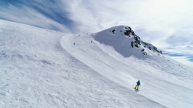 Skiers and snowboarders riding down the mountain slope. Aerial flight above mountain ski resort Gudauri, Georgia
