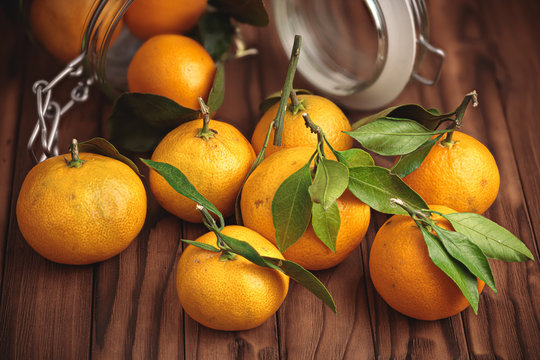 tangerines and glass jar on wooden surface