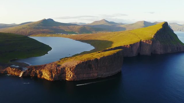 Aerial drone video flying over Bosdalafossur waterfall on Sorvagsvatn lake in sunset time. Vagar island, Faroe Islands, Denmark. UHD 4k video