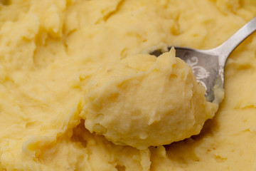 top view close up of mashed yellow potatoes texture with spoon in it