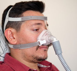 young white man with sleep apnea using CPAP machine and wearing nasal mask