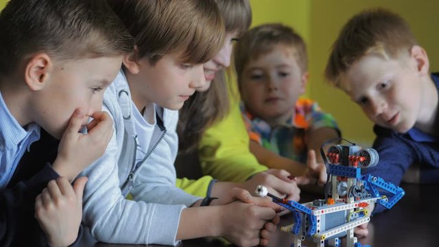 Children in the classroom make figures with teacher. Modern technology concept