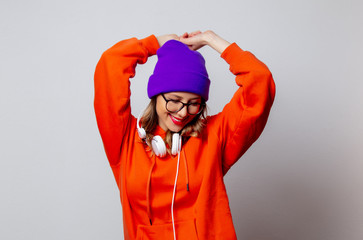 Style girl in orange hoodie and purple hat with headphones