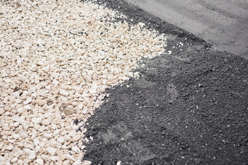 Closeup new hot asphalt. Laying asphalt, covering the pit, on the rubble. Asphalt Compactors is carrying out road repair work.