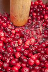 Crush the red cranberry berries with a wooden rolling pin