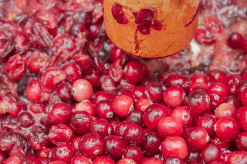 Crush the red cranberry berries with a wooden rolling pin