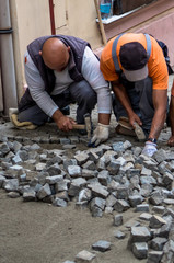 Team Of Construction Workers Building Pavement With Cobblestones
