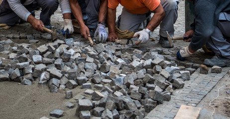 Team Of Construction Workers Building Pavement With Cobblestones