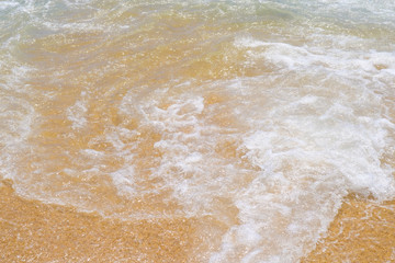 Fototapeta na wymiar Wave on wet beach sand. The clear water and sand on the Mediterranean Sea on Costa Brava, Spain.