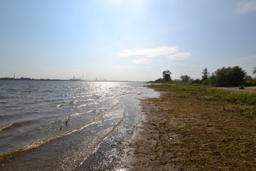 Sunny morning, small waves roll on the bank of Kama near the Usolye 