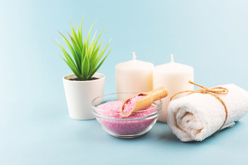 Beauty or relaxation composition on blue background. Pink bath salt, towels, candles. Stress relief.