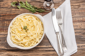 Homemade fettuccine with bechamel sauce in a white plate, rustic wooden table background, soft light - Italian food style