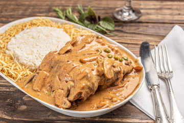 Beef with mushroom, rice and potato in a white plate on wooden white background. Soft light. Italian food.