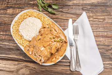 Beef with mushroom, rice and potato in a white plate on wooden white background. Soft light. Italian food.